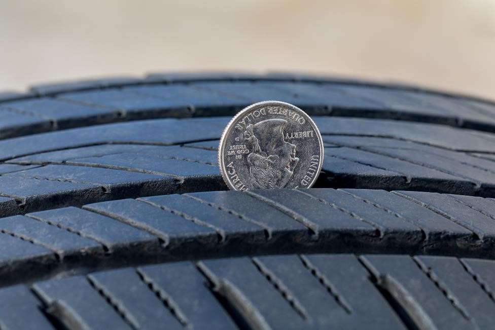 Using a quarter to test the tire tread depth on a tire.