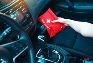 A woman places her first aid kit in the glove box of her car.