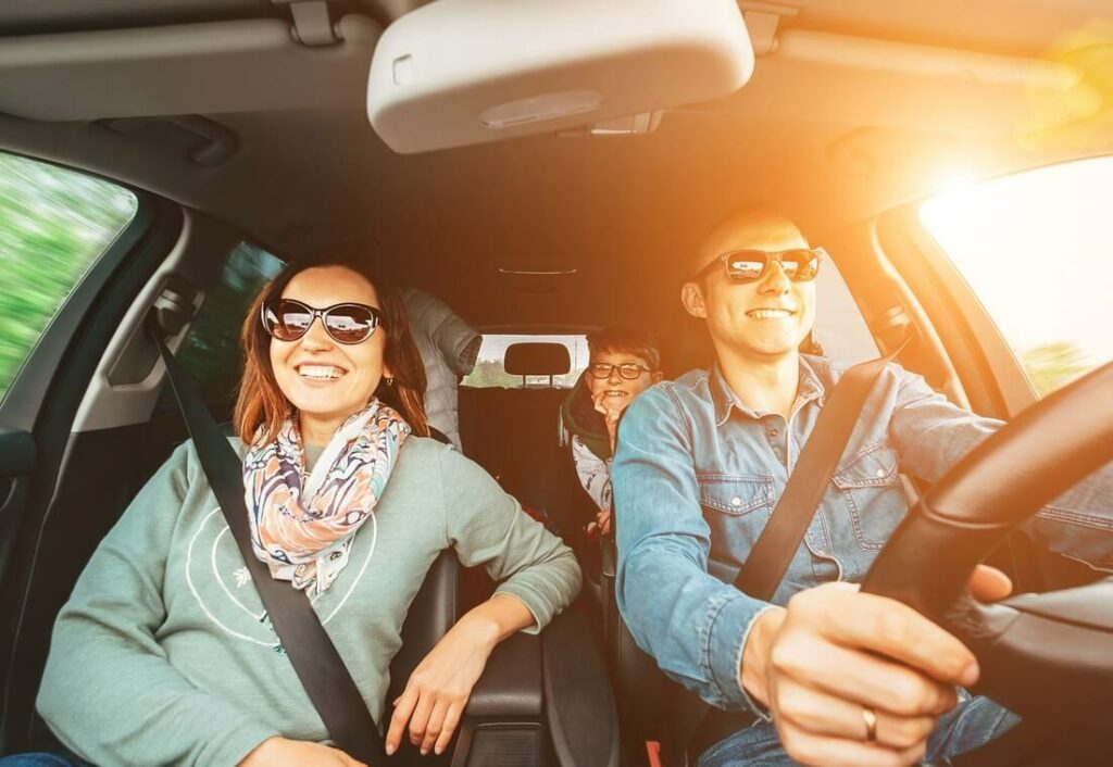 Happy family driving with the sun shining through the window.