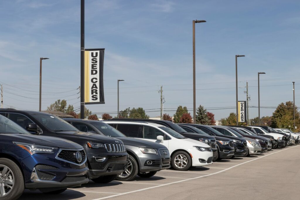 A line of used cars for sale at a dealership.