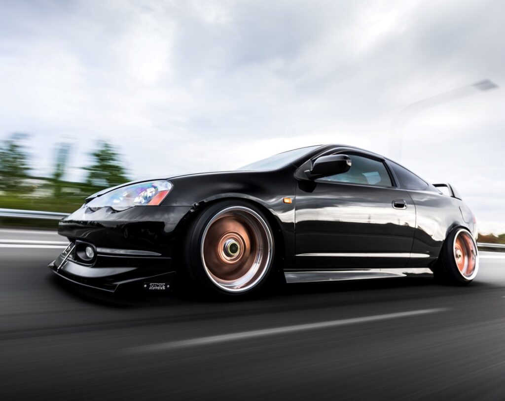 A black Acura Integra on the highway with a blurred background.