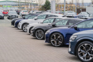 A row of Audis parked in a car dealership lot during the day.