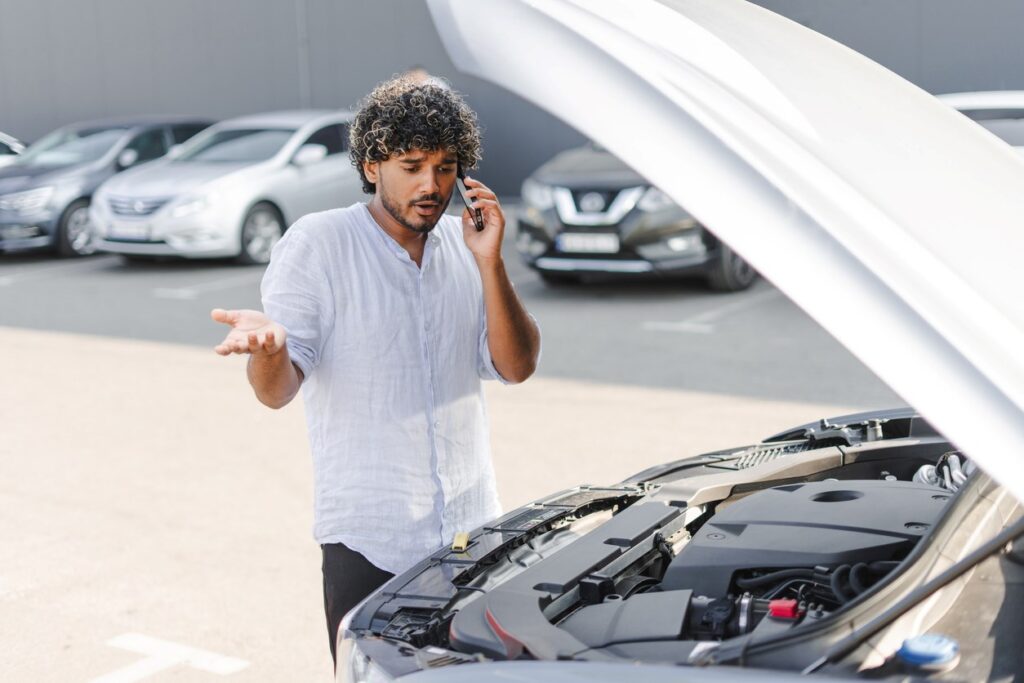 A frustrated young man calls for a towing service after his car breaks down.