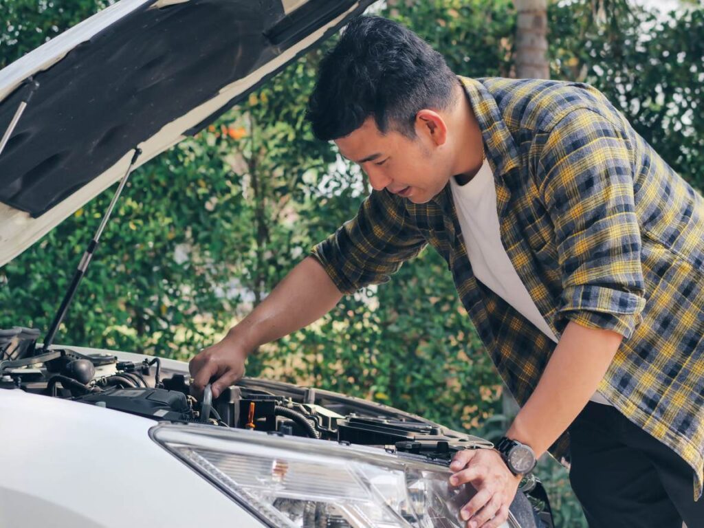 Man looking under hood of car.
