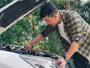 Man looking under hood of car.