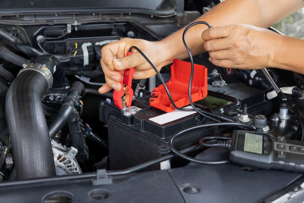 A mechanic uses a meter to check the charge in a car battery.