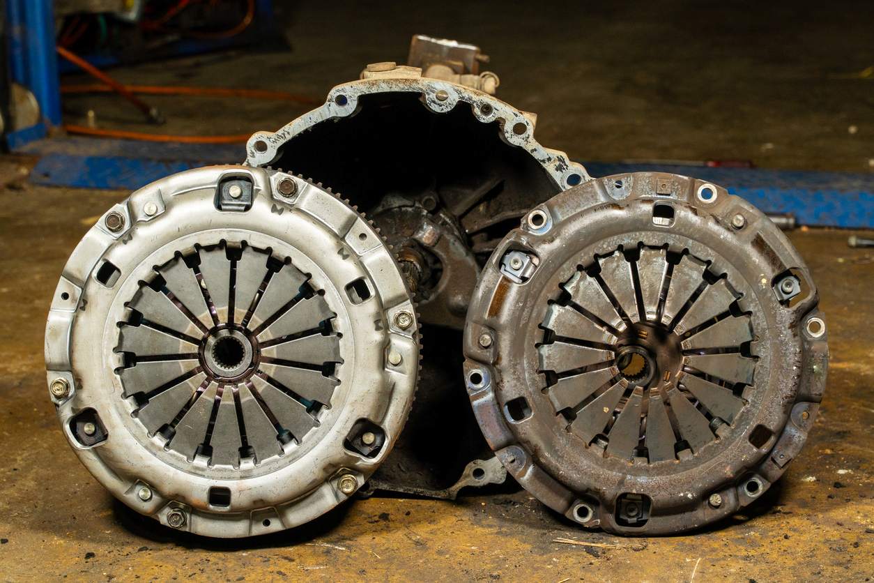 A comparison of two transmission clutch plates, one old and one new, from a truck, showing the level of wear.