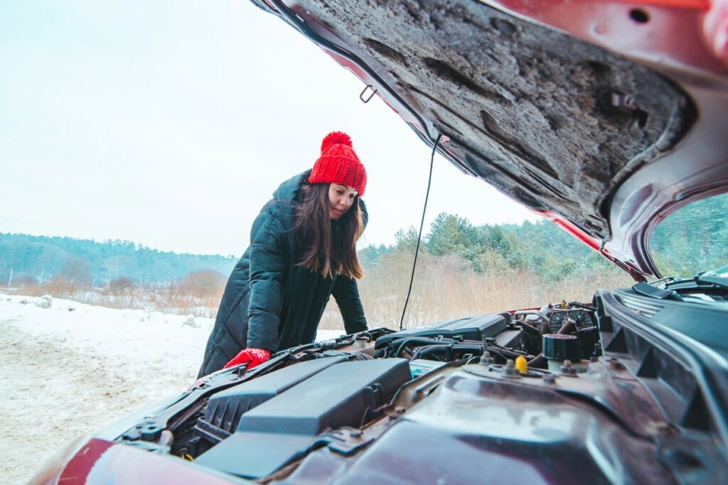 Woman looking at car engine road assistance concept winter season