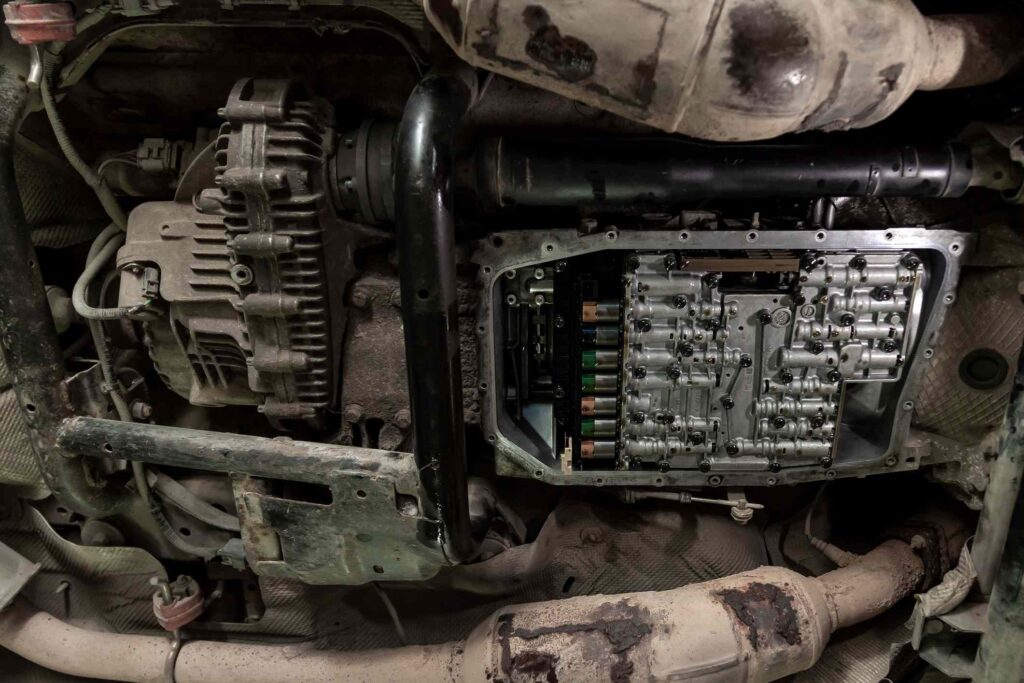 Bottom view of the bottom of a car with the transmission pan removed and a view of the solenoids lubricated with oil during repair and maintenance in a workshop for vehicles.